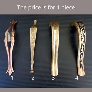 May include: Four antique metal handles in various designs. The handles are numbered 1 through 4. Handle 1 is copper-colored with green accents. Handles 2, 3, and 4 are gold-colored, with handle 4 featuring black and gold floral detailing.