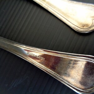 May include: Two silver-plated spoons with heart-shaped ends. The spoons are marked "SILVER PLATED" on the back.