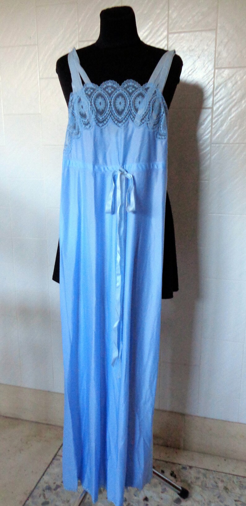 May include: A light blue satin nightgown with a lace trim and a bow at the waist.