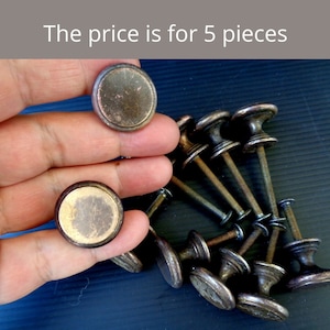 Op de afbeelding: Een verzameling antieke, bronskleurige kastknoppen met een rond, plat ontwerp. De knoppen hebben een verweerde afwerking en de afbeelding bevat de tekst "The price is for 5 pieces."