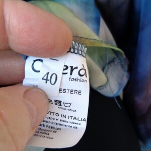 May include: A close-up of a clothing tag with the number 40 and the brand name "Cer&agrave; fashion". The tag also includes washing instructions and the text "PRODOTTO IN ITALIA". The fabric has a colorful, watercolor-like pattern.
