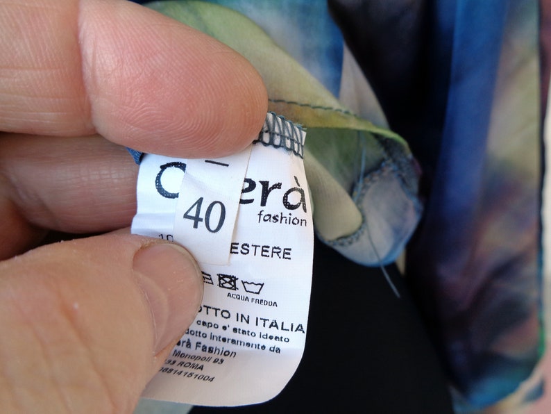 May include: A close-up of a clothing tag with the number 40 and the brand name "Cer&agrave; fashion". The tag also includes washing instructions and the text "PRODOTTO IN ITALIA". The fabric has a colorful, watercolor-like pattern.