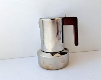 May include: A stainless steel stovetop espresso maker with a dark brown handle. The coffee pot has a shiny, reflective surface and a classic design, perfect for brewing espresso at home.