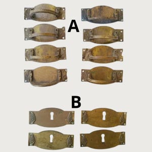 Può includere: Una collezione di otto maniglie per cassetti in ottone etichettate A, con impugnature curve e piastre rettangolari con motivi decorativi, e quattro bocchette per serratura in ottone etichettate B, ciascuna con apertura centrale e dettagli a goccia.