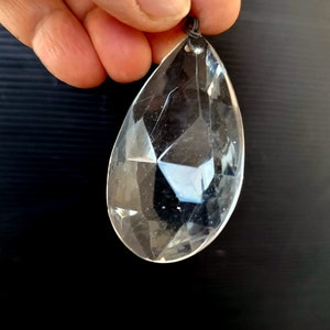Peut inclure: Un prisme en cristal transparent en forme de larme avec une boucle de fil argenté en haut.