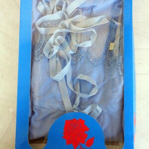 May include: A blue lace nightgown with a white ribbon, packaged in a blue box with a red rose illustration.