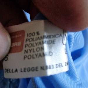 May include: A white tag with black text that reads "100% Poliammidica Polyamide Nylon Polyamid Della Legge N. 113 del 26"