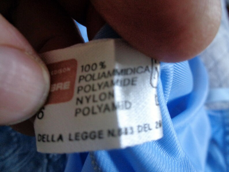 May include: A white tag with black text that reads "100% Poliammidica Polyamide Nylon Polyamid Della Legge N. 113 del 26"