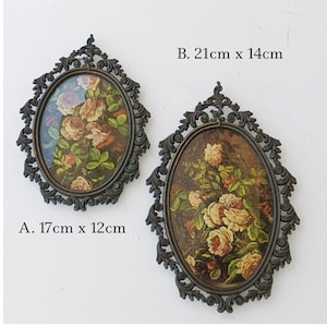 Può includere: Due opere d'arte da parete ovali in stile antico. Le cornici sono in bronzo scuro con dettagli ornati. L'opera d'arte all'interno presenta composizioni floreali con rose nei toni del rosa, crema e rosso. Una misura 17 cm x 12 cm, l'altra 21 cm x 14 cm.