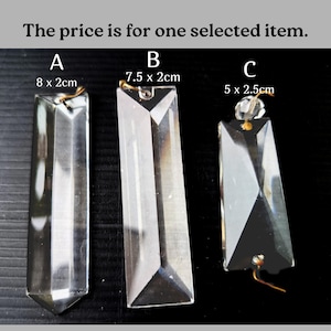 Op de afbeelding: Drie heldere kristallen prisma hangers met goudkleurige draadbevestigingen. De hangers zijn gelabeld A, B en C, met afmetingen van 8 x 2 cm, 7,5 x 2 cm en 5 x 2,5 cm. De tekst bovenaan luidt: "De prijs is voor één geselecteerd item."