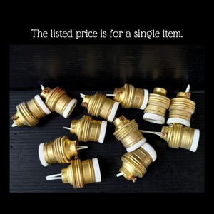 May include: A selection of brass-coloured light bulb sockets with white ceramic bases and exposed wiring. The text "The listed price is for a single item" is visible at the top of the image.