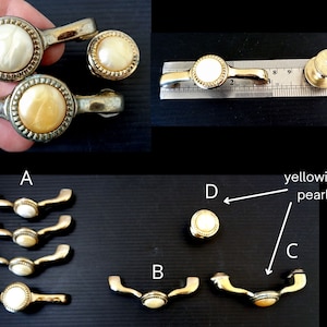 May include: A collection of vintage drawer pulls and knobs. The hardware features a yellowish pearl center surrounded by a gold-toned metal frame. The pulls have a curved handle design. Some pieces are shown with a ruler for size reference.
