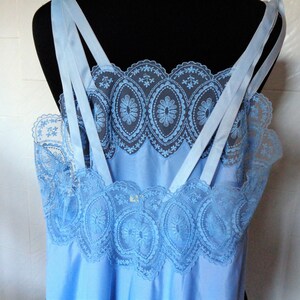 May include: A light blue slip with delicate lace trim. The straps are made of satin and have a criss-cross design.