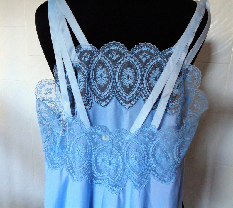 May include: A light blue slip with delicate lace trim. The straps are made of satin and have a criss-cross design.