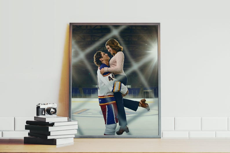 May include: Framed print featuring a couple embracing on an ice hockey rink. The man wears a hockey jersey with the number 44. The woman is wearing a pink sweater and dark pants. The background shows the arena.