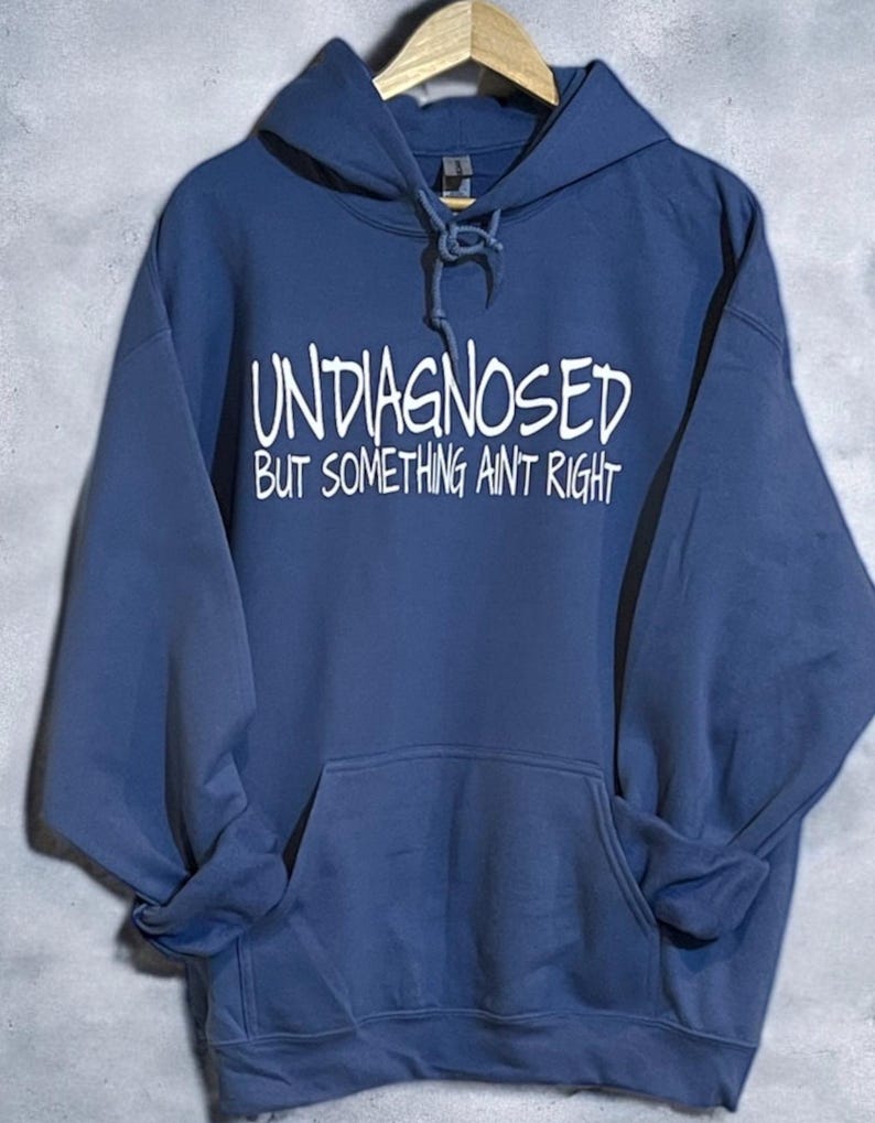 May include: A blue hooded sweatshirt with the text "UNDIAGNOSED BUT SOMETHING AINT RIGHT" in white.