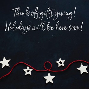 May include: A dark blue background with white text saying "Think of gift giving! Holidays will be here soon!" Below, a red string is decorated with white star-shaped ornaments. A festive seasonal image.