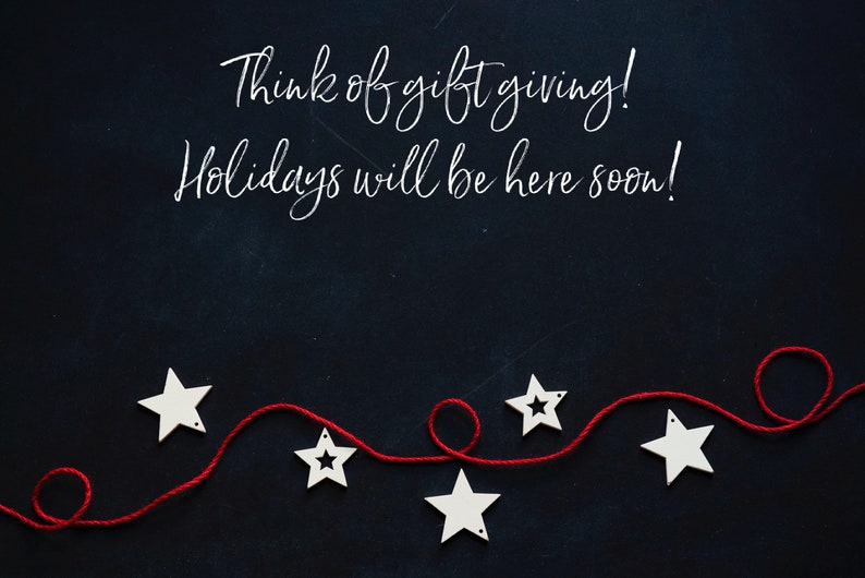 May include: A dark blue background with white text saying "Think of gift giving! Holidays will be here soon!" Below, a red string is decorated with white star-shaped ornaments. A festive seasonal image.