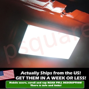 May include: A white rectangular light fitting with a black frame is mounted to a red surface. The light is on and illuminating the area. The text "square" is visible in the image.