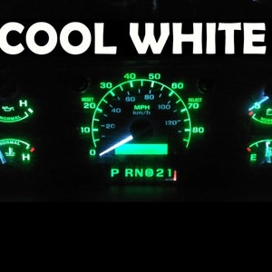 Puede incluir: Un tablero de instrumentos de un automóvil con un velocímetro, un indicador de combustible, un indicador de presión de aceite y un indicador de batería. Los indicadores están iluminados en verde y blanco. El velocímetro marca 0 y el texto "COOL WHITE" se muestra en la parte superior de la imagen.