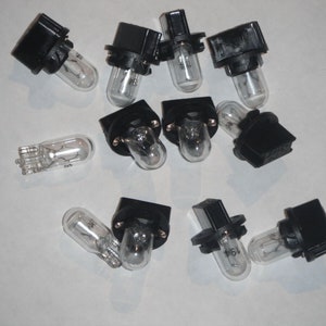 Puede incluir: Un grupo de 12 portalámparas de plástico negro con bombillas de vidrio transparente. Las bombillas son todas del mismo tamaño y forma, y están dispuestas en un patrón aleatorio.