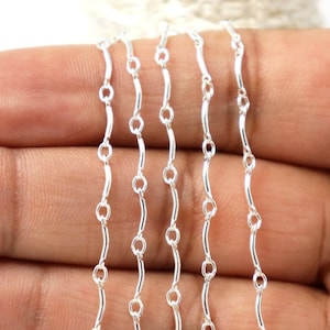 May include: Silver chain with a delicate, curved link design. The chain is shown in multiple strands, highlighting its flexibility and shine.