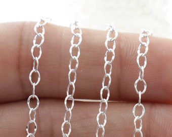 May include: A close-up of a silver chain, with multiple strands of the chain laid out on a hand. The chain is made of small, oval-shaped links.