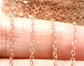 Op de afbeelding: Drie strengen van een roségouden ketting, ongeveer 45 cm lang, worden getoond op de hand van een persoon. De ketting is delicaat en heeft een fijne, gladde afwerking.