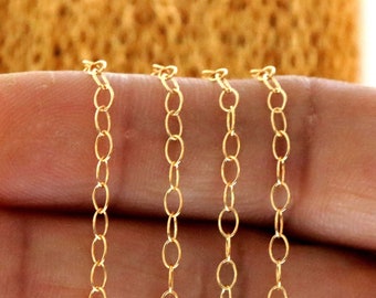 May include: Four strands of gold chain, each with a different length, are displayed on a hand. The chains are made of small, oval-shaped links.