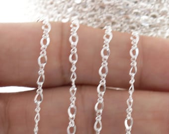 May include: Silver chain in a variety of lengths, shown on a hand. The chain is a delicate, oval-link style.