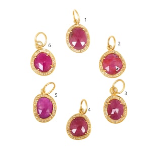 May include: Six gold pendants with pink ruby stones surrounded by small diamonds. Each pendant has a loop at the top for attaching to a chain.
