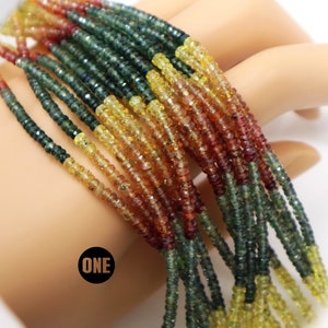 May include: A strand of multi-colored gemstone beads. The beads are small and round, and they are arranged in a rainbow pattern. The colors of the beads are green, yellow, and red.