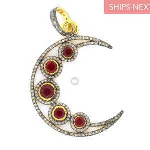 May include: A silver crescent moon pendant with a gold bail and five red gemstones set in a circle of diamonds.