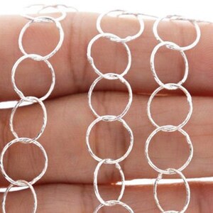 May include: Silver chain with a textured, circular link design. The chain is shown in three rows, with each row featuring a different length.