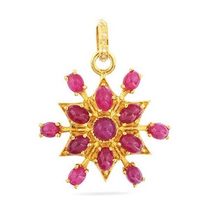 May include: A gold pendant with a starburst design featuring a central ruby surrounded by smaller rubies.