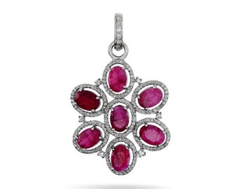May include: A silver pendant with a flower-shaped design featuring seven oval-shaped ruby gemstones surrounded by smaller diamonds.