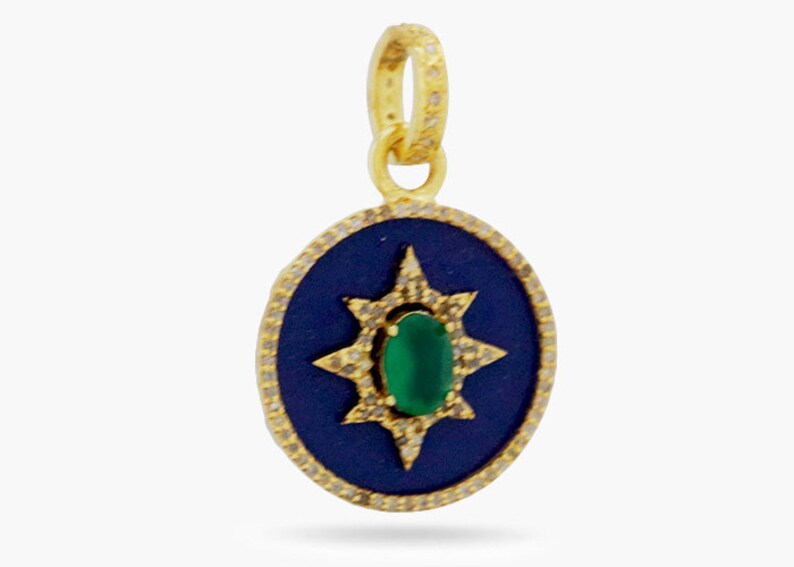 K&ouml;nnte beinhalten: Ein goldener Anh&auml;nger mit einem blauen Emaille-Oval-Anh&auml;nger, der einen gr&uuml;nen Edelstein zeigt, der von einem Sternburst-Design mit klaren Steinen umgeben ist.