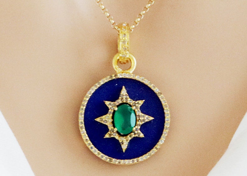 K&ouml;nnte beinhalten: Goldkette mit einem blauen und gr&uuml;nen Anh&auml;nger mit einem Sternendesign und einem gr&uuml;nen Edelstein in der Mitte.