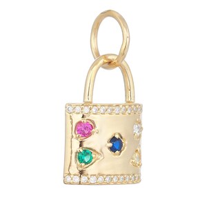 May include: A gold padlock charm featuring a row of small clear stones along the top and bottom edges. The center surface is decorated with a pink, a blue, and a green round gemstone, along with two additional clear stones on the right side.