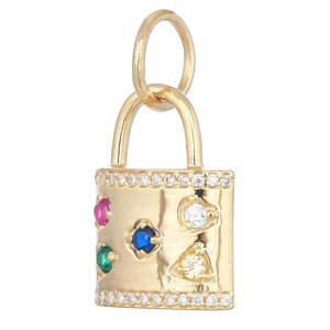 May include: A gold padlock charm featuring a row of small clear stones along the top and bottom edges. The front surface is decorated with five larger, multi-colored inset stones in red, blue, green, white, and yellow, and a gold jump ring.