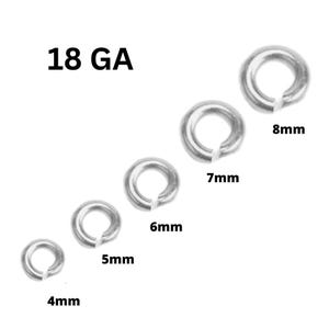 May include: A collection of silver-colored jump rings in various sizes, ranging from 4mm to 8mm. The text "18 GA" is displayed above the rings, indicating the gauge of the wire used. These rings are commonly used in jewelry making and crafts.