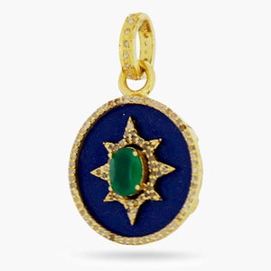 K&ouml;nnte beinhalten: Ein goldener Anh&auml;nger mit einem blauen Emaille-Kreis und einem gr&uuml;nen Edelstein in der Mitte. Der Kreis ist von einem goldenen Sternburst-Design mit kleinen wei&szlig;en Edelsteinen umgeben.