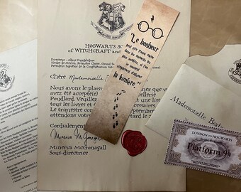 May include: A collection of printed stationery including a Hogwarts acceptance letter, a list of school supplies, a cream-colored envelope, a rectangular bookmark with glasses and French text, and a Platform 9 3/4 ticket with a red wax seal.