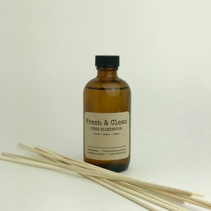 May include: A brown glass bottle with a black lid and a label that reads "Fresh & Clean Odor Eliminator Lime, Orange, Lemon Air Diffuser | Certified Clean Scents Handmade in Idaho | UpNorthGoodThings.com"