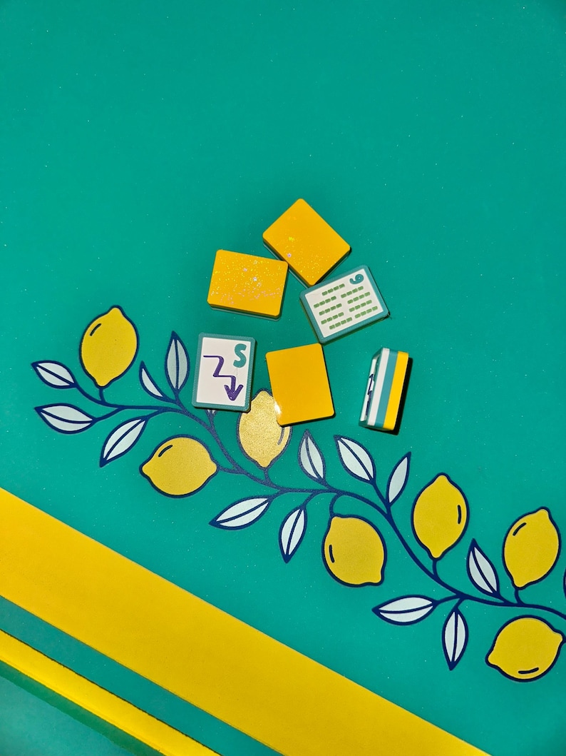 May include: A teal background with yellow accents and several small, yellow, rectangular objects. A yellow and white lemon branch design is on the left. The image has a playful, summery vibe.