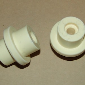 May include: Two white ceramic round pieces with a hole in the center. One piece is stacked on top of another piece.
