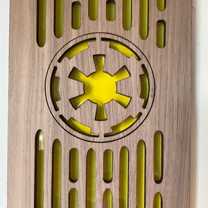 May include: A wooden plaque with a yellow Imperial symbol from Star Wars. The plaque has a repeating pattern of yellow ovals.