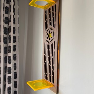 May include: A wooden wall shelf with a Star Wars Imperial symbol and two yellow acrylic shelves.