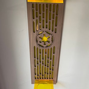 May include: A wooden wall decor with a yellow Imperial symbol and a yellow acrylic shelf. The decor has a repeating pattern of yellow ovals.