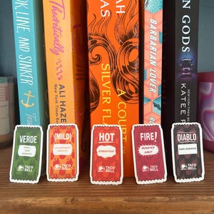 Puede incluir: Cinco paquetes de salsa Taco Bell, cada uno con un nivel de picante y un perfil de sabor diferentes. Los paquetes están etiquetados como "Verde", "Mild", "Hot", "Fire!" y "Diablo".